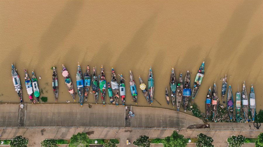 Colorful wooden river boats moored side by side along the riverbank in Phnom Penh, seen from above