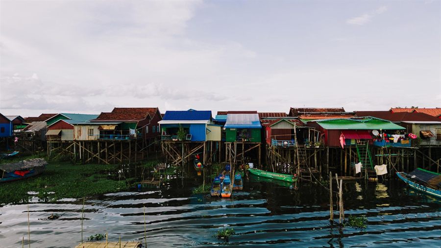 Brightly painted stilt houses reflected in the water at Kampong Khleang on the Tonle Sap