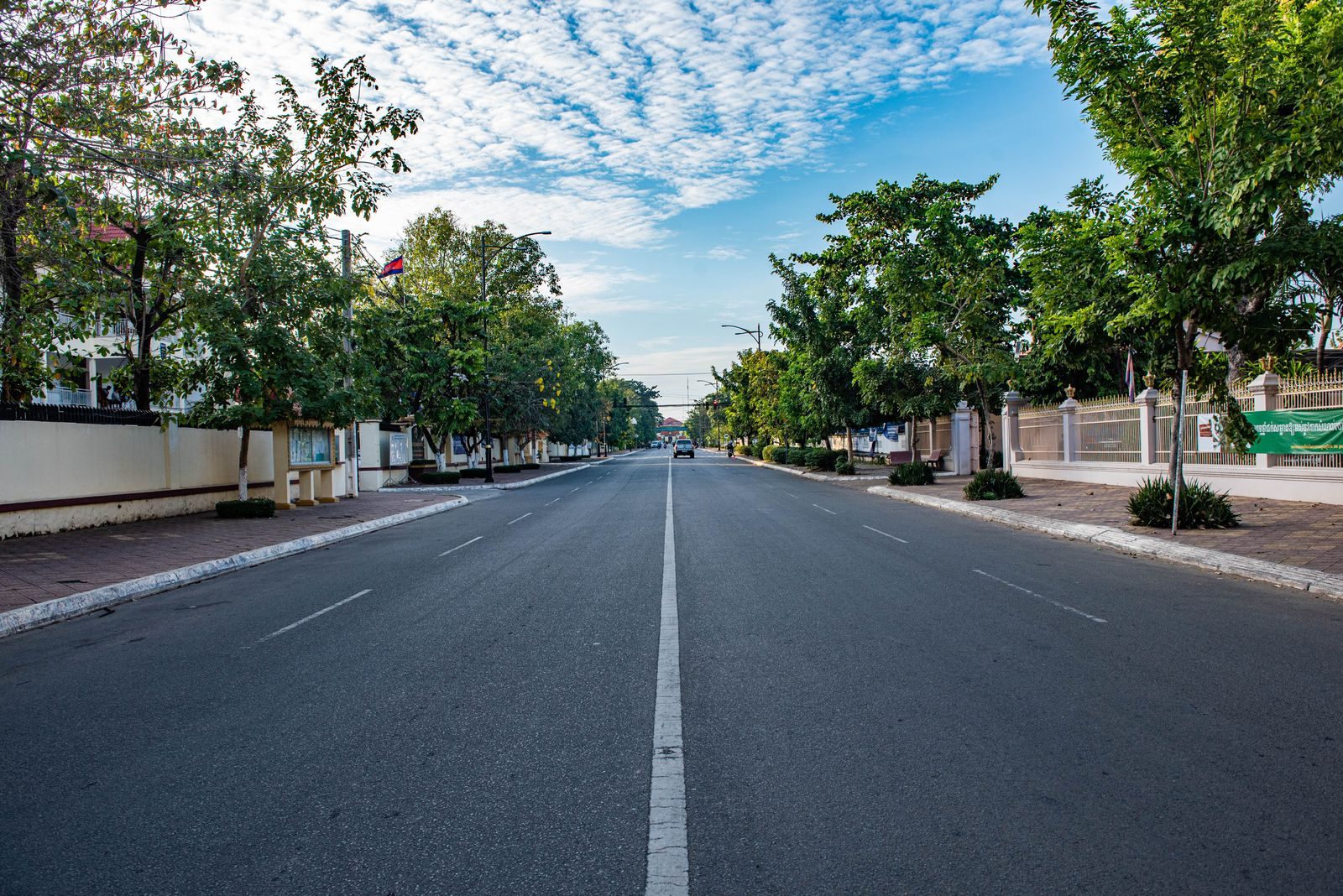 Quiet tree-lined street in Kampong Cham town, Cambodia, under a blue sky
