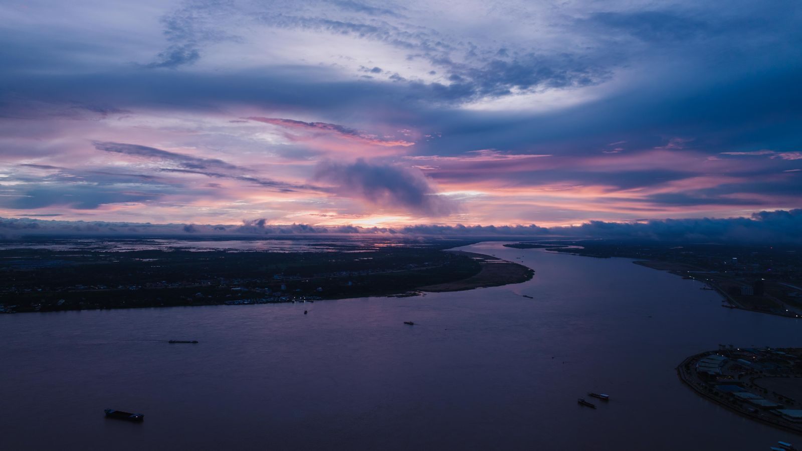 Purple and orange sunset over a broad bend of the Mekong in Cambodia, the hour guests watch from the deck of a Cambodia luxury river cruise
